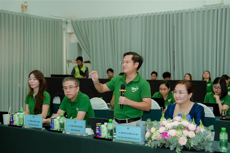 A person in green shirt speaking to a group of people  Description automatically generated