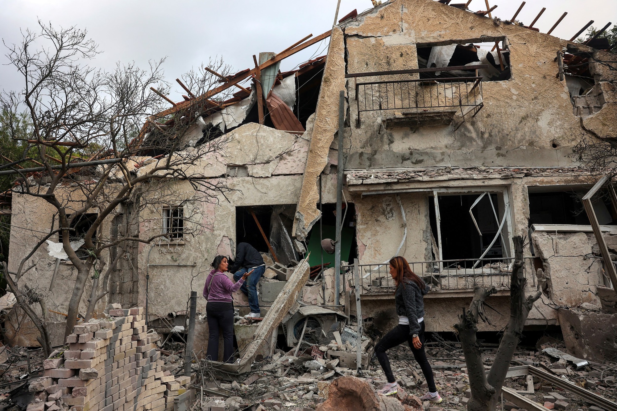 People check their family's damaged house at the scene where one of the projectiles fell, after projectiles crossed over to Israel from Lebanon, in Rinatiya