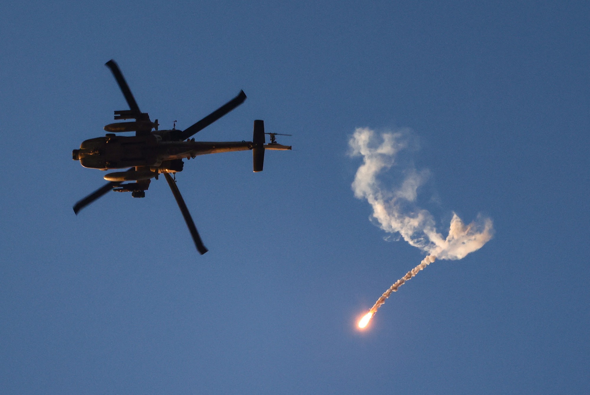 An Israeli military Apache helicopter releases a flare as it flies near the Israel-Gaza border