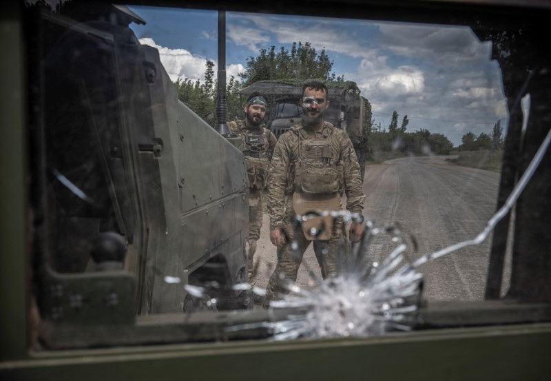 Ukrainian servicemen pose for a picture as they repair a military vehicle near the Russian border in Sumy region