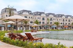 A pool with lounge chairs and umbrellas in front of a building  Description automatically generated