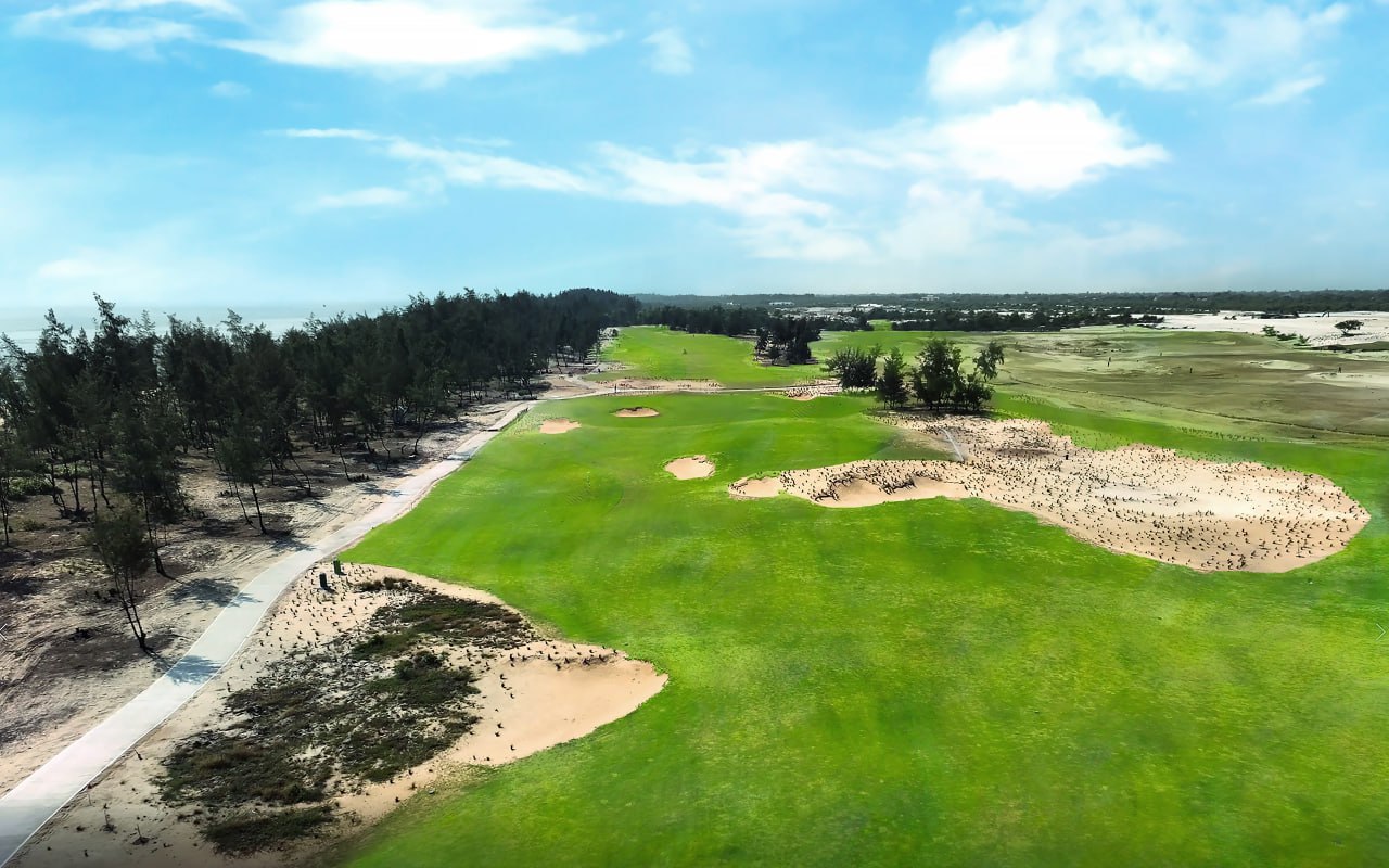 A golf course with sand bunkers and trees  Description automatically generated