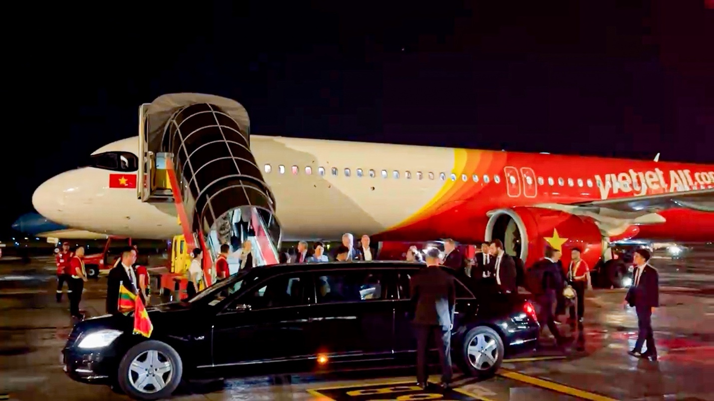 Tổng thống Litva đến Hà Nội trên chuyên cơ Vietjet- Ảnh 3. A group of people boarding an airplane Description automatically generated