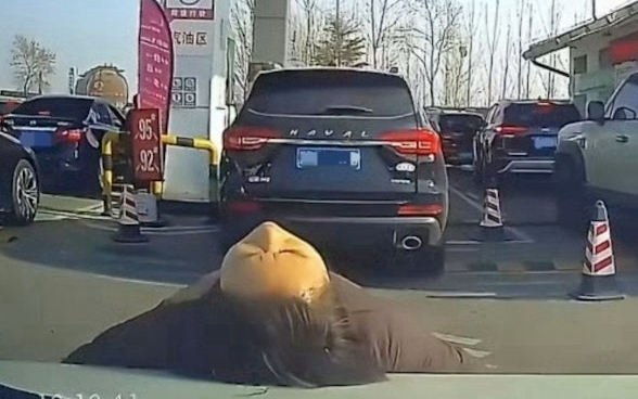 Người phụ nữ nằm lên capo xe để chen hàng đổ xăng gây tranh cãi ở Trung Quốc