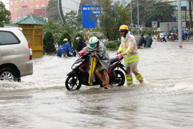 Chiến sĩ cảnh sát giao thông giúp người dân đẩy xe ra khỏi vùng ngập,