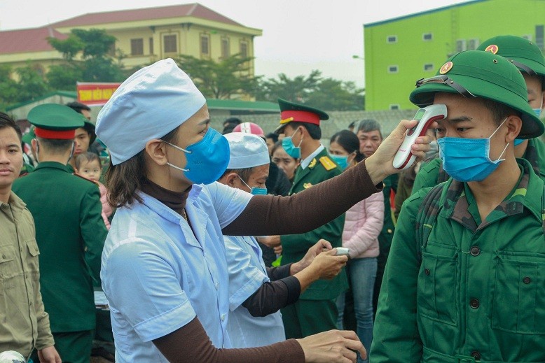 Các tân binh được trang bị khẩu trang y tế và được đo thân nhiệt trước khi bước vào buổi lễ giao quân. 