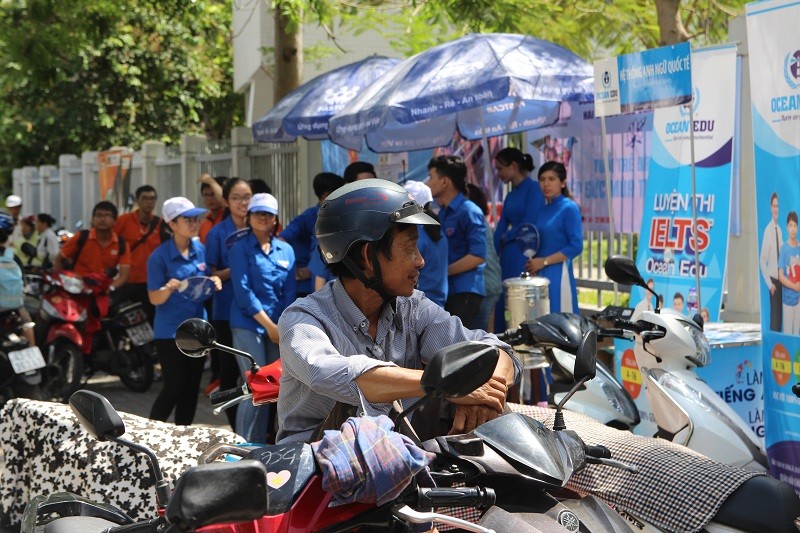 Bất chấp cái nắng, người này ngồi luôn trên xe máy đợi con. Gương mặt khá lam lũ, nhưng nụ cười của ông rất tươi.