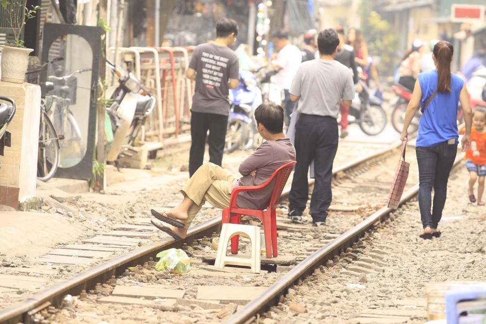 Người đàn ông mang ghế ngồi ngay trong lòng đường sắt.