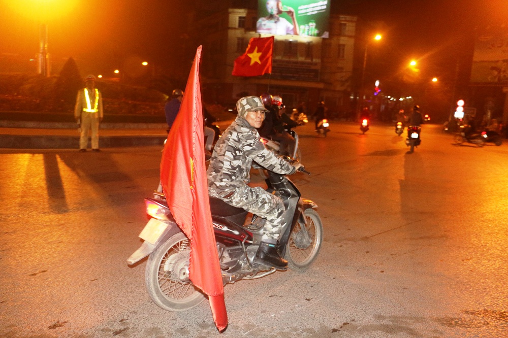 Người đàn ông trong trang phục rất bắt mắt, mang theo cờ tổ quốc trên xe để hòa vào dòng người trên đường Lê Mao.