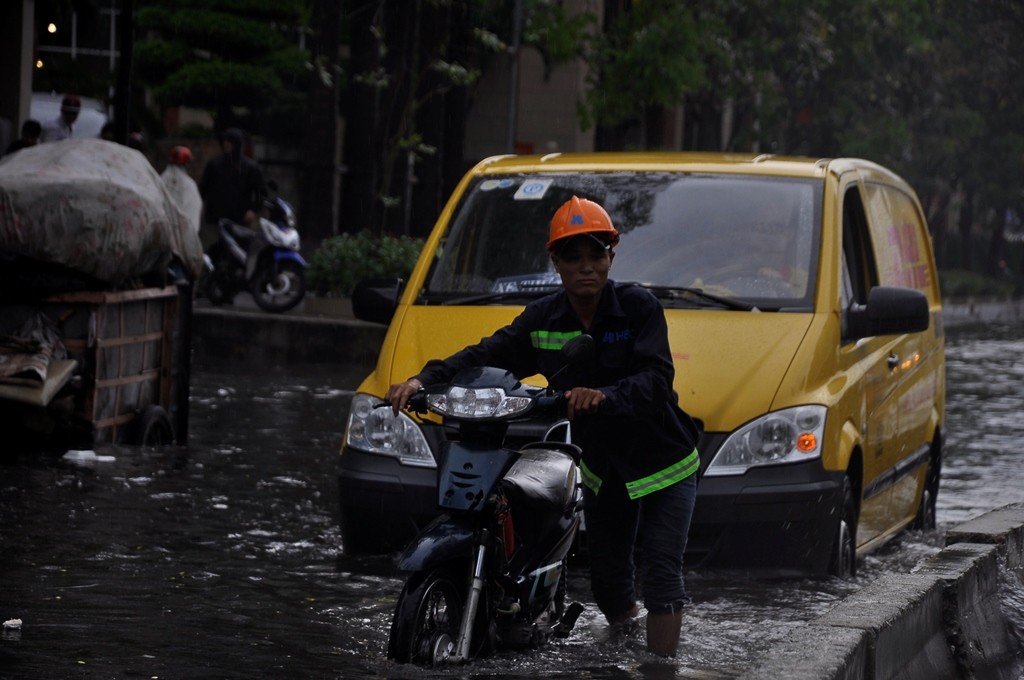 Một công nhân phải dắt bộ vì xe máy ngập và chết máy.