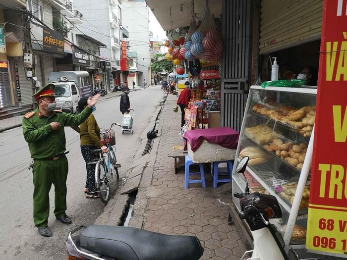 Công an phường Vĩnh Tuy (Hai Bà Trưng) nhắc nhở người dân, hộ kinh doanh thực hiện đúng chỉ thị của Thủ tướng Chính phủ. (Ảnh: Thanh Tùng/TTXVN)