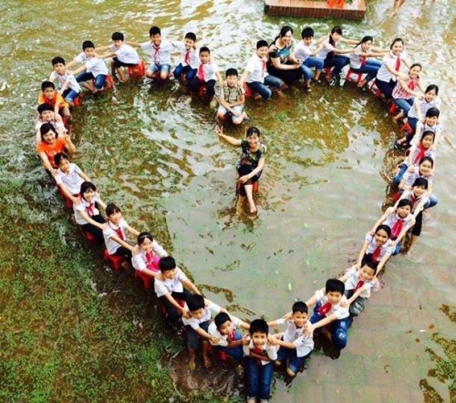 Xã hội - HS lớp 5 xếp hình trái tim chụp ảnh kỷ yếu giữa sân trường ngập nước