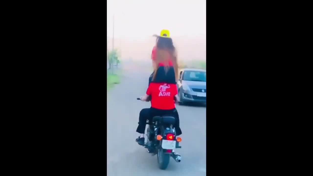 Hai cô gái ngồi lên cổ nhau chạy xe máy