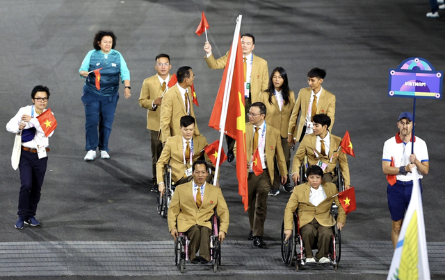 Đoàn thể thao Việt Nam diễu hành trong lễ khai mạc Paralympic Paris 2024 với người cầm cờ là đô cử Lê Văn Công (trái, hàng đầu).