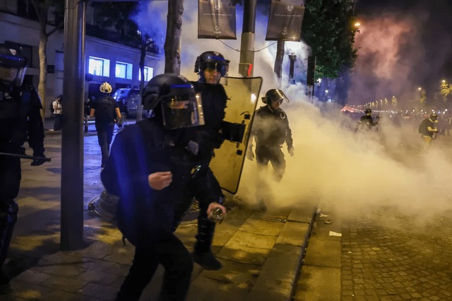 Cảnh sát đụng độ với người hâm mộ PSG đang ăn mừng trên đại lộ Champs-Elysees. (Ảnh: EPA)