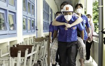 Tình nguyện viên cõng thí sinh bị gãy chân, ngồi xe lăn vào phòng thi