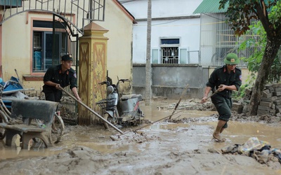 Cảnh sát cơ động giúp dân dọn bùn đất sau mưa lũ